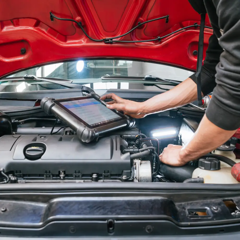 Diagnostic automobile moderne | BC AUTO Mécanicien utilisant un outil de diagnostic sur un moteur.
