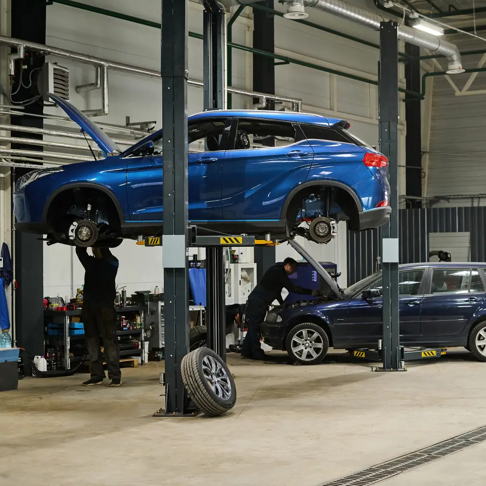 Réparation automobile en atelier | BC AUTO Atelier de réparation automobile avec deux voitures sur des ponts élévateurs.