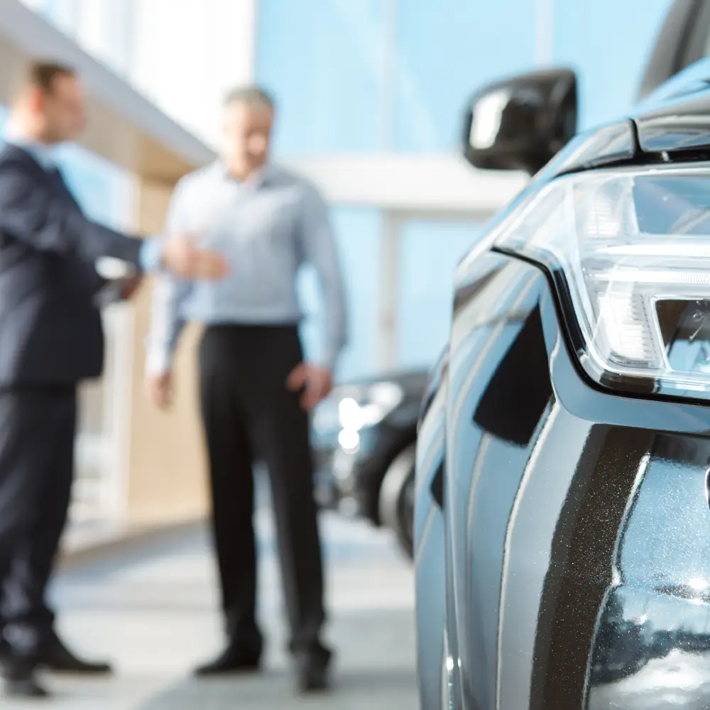 Voiture et discussion en arrière-plan | BC AUTO Voiture en gros plan avec deux hommes en arrière-plan