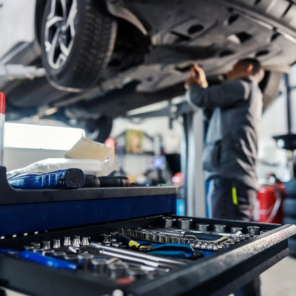 Réparation automobile en atelier | BC AUTO Mécanicien travaillant sous une voiture surélevée